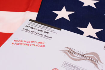 Return envelope for official vote by mail ballot. Background the flag of the United States. Selective focus. - San Jose, California, USA - October 8, 2020