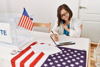 Brunette woman with down syndrome writing on clipboard speaking on the phone at election room