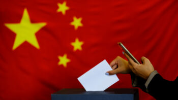 Hand holding ballot paper for election vote concept. elections, The hand of woman putting her vote in the ballot box. China Flag on background