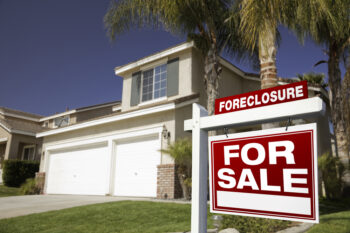 Red Foreclosure For Sale Real Estate Sign in Front of House.
