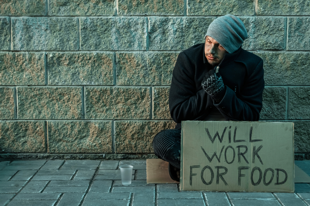 A man, homeless, a man asks for alms on the street with a sign will work for food. Concept of homeless person, addict, poverty, despair A man, homeless, a man asks for alms on the street with a sign will work for food. Concept of homeless person, addict, poverty, despair